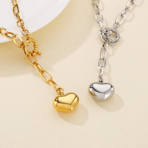 Macro detail of gold and silver heart pendant necklaces with OT clasp on chunky square links