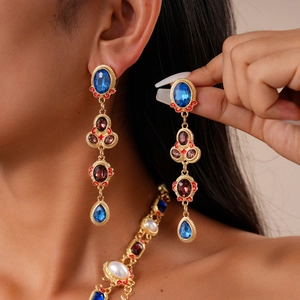 Detail of vintage court style gold drop earrings with blue gemstones and small red diamonds