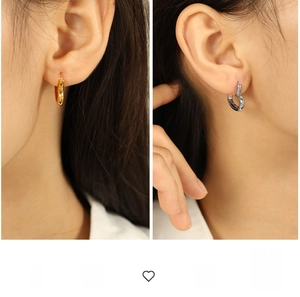 Detail showing polished gold and silver chunky heart hoop earrings on human ear