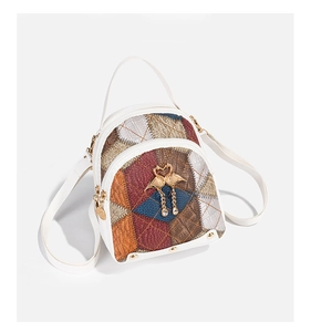 Détail du sac à dos blanc avec motif à losanges colorés et pendentifs de cygne dorés