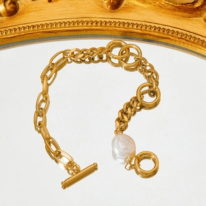 Elegantes goldenes Gliederkettenarmband mit großer Perle und Knebelverschluss auf Spiegel