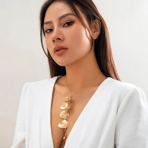 Detail of golden ginkgo leaf tassel necklace on model with minimalist white top