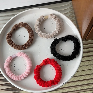 Detailed close-up of five colorful velvet scrunchies with matte buckles on a ceramic tray