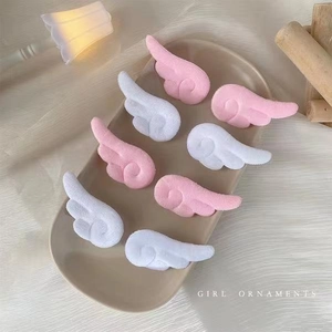 Detailansicht der flauschigen rosa und weißen Engelsflügel-Haarspangen auf Keramik
