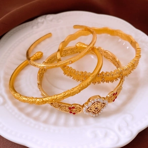 Detailed macro shot of vintage gold four-leaf bracelets with pearls on a white plate