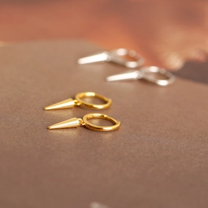 Detailed macro view of S925 sterling silver hoop earrings with polished cone pendants