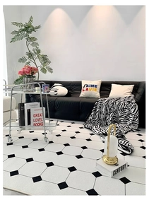 Modern living room setting featuring a soft geometric patterned rug with black tile motifs