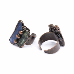 Close-up of handmade bronze rings set with blue and green raw natural crystal stones