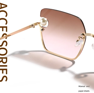 Macro detail of gold metal frame with large pearl accent on square gradient sunglasses