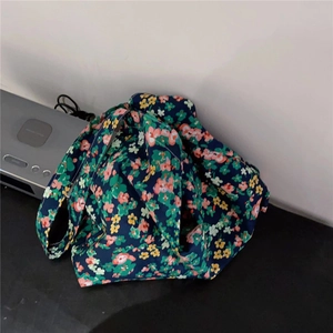 Detailed texture of dark blue floral tote bag with green leaves and colorful blossoms