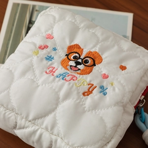 Vue détaillée du chien brodé sur une trousse de maquillage matelassée blanche