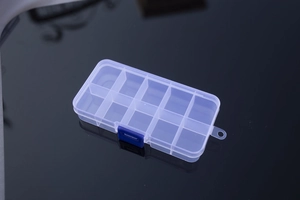 Macro shot of 10-compartment transparent storage box with a blue latch on black background