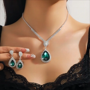 Detail of emerald teardrop pendant necklace and earrings set on a model