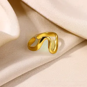 Macro detail of wave shaped gold ring on silk fabric highlighting glossy polished finish