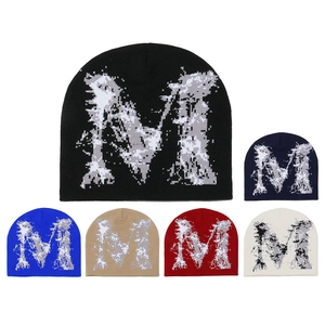 Détail de bonnets en maille jacquard avec motif lettre M en six coloris différents