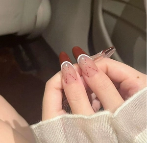Close-up of almond-shaped press-on nails with French tip design and red cross pattern
