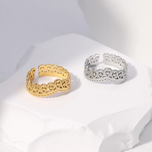 Detail of adjustable crown rings in gold and silver finish on a white stone base