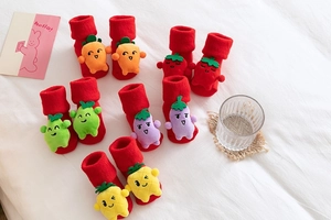 Detail of red Christmas baby socks with 3D cartoon fruit and vegetable decorations