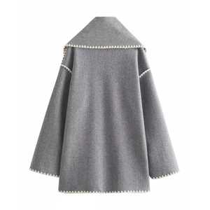Detail view of grey wool coat back with white scalloped wave embroidery on edges