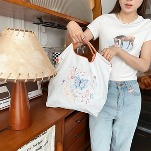 Détail de la broderie papillon sur le sac en toile blanc cassé avec anse orange