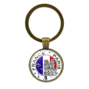 Primer plano del llavero de bronce souvenir de Francia con Notre Dame y la bandera