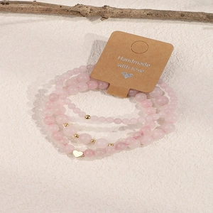 Detail of pink crystal beaded bracelet with gold heart charm on handmade paper card