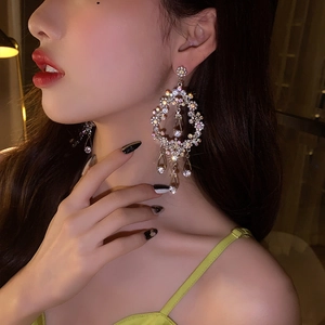 Elegant oversized silver flower vine earrings with sparkling crystals worn by a model