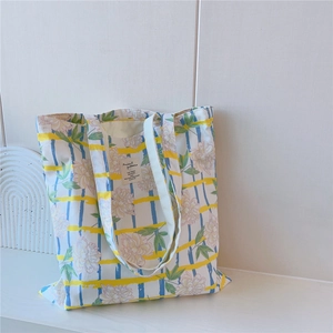 Détail du sac fourre-tout en coton avec motifs floraux et rayures jaunes et bleues