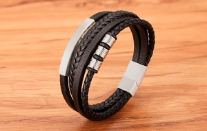 Detail of multi-layer black braided leather bracelet with silver polished metal plate