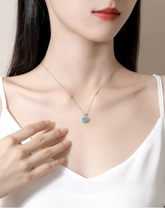 Detail view of the round blue sapphire pendant on a fine S925 silver chain worn by a model