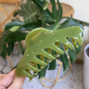 Macro detail of a 14cm fruit green claw clip with large dragon bone teeth for thick hair