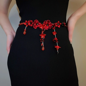 Detail der roten Blumen-Taillenkette mit schwarzen Perlen auf einem schwarzen Kleid