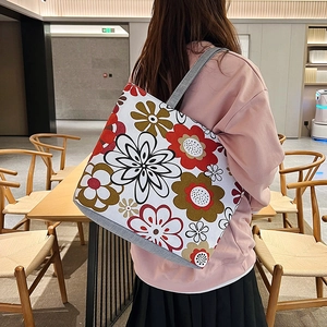 Detailed shot of large floral canvas tote bag shown by female model in casual attire