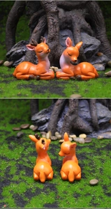 Detail von süßen orangefarbenen Reh-Harzfiguren in einer Mikrolandschaft im Wald