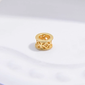 Macro detail of golden hollow spacer bead with antique coin pattern for DIY jewelry