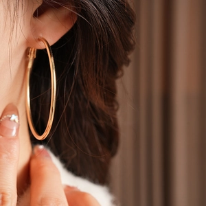 Close-up of a large polished gold hoop earring worn for a minimalist vintage fashion look