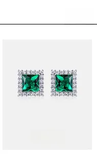 Macro shot of square-cut emerald stud earrings with halo micro-pave diamond setting