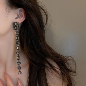 Macro shot of long tassel earrings with dark square crystals on a fashion model