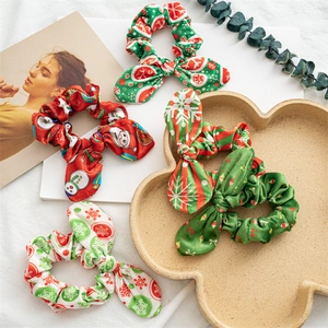 Flat lay macro of five festive Christmas scrunchies with Santa and snowflake patterns