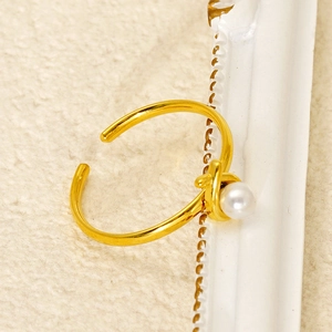 Dettaglio dell'anello in acciaio al titanio dorato con perla bianca in stile vintage