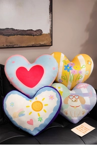 Close-up of four assorted heart-shaped plush pillows displayed on a cozy sofa