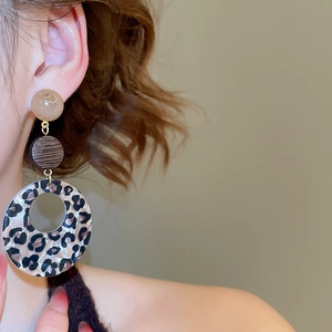 Close-up of leopard print acrylic drop earrings with three-tier geometric circular design