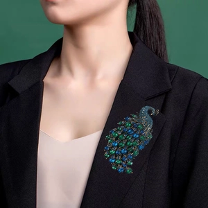 Vintage crystal peacock brooch with blue and green rhinestones on a black suit blazer