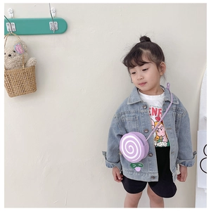 Detail of child wearing a purple lollipop shoulder bag with white swirl and leaf decor