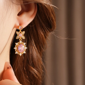 Detailed view of vintage gold earrings with pink oval zircon and bow-knot design