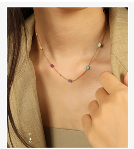 Close-up of golden necklace with colorful square enamel charms on a female model