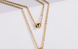 Macro shot of gold ball pendant necklace featuring polished O-chain on white background