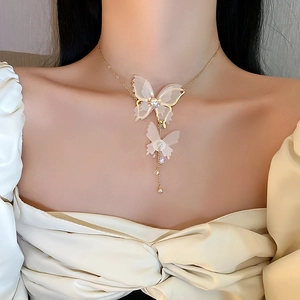 Vue détaillée du collier pendentif double papillon avec perles et élégants pompons