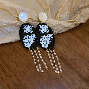 Detailed shot of bamboo style earrings with pearl tassels on vintage wood background