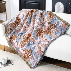 Retro floral jacquard throw blanket with fringe draped on a white sofa in a modern room